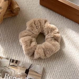 Primo piano di un morbido elastico per capelli in peluche kaki su tessuto beige autunnale