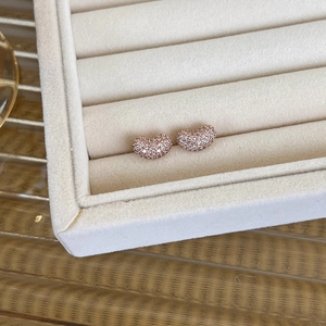 Macro view of rose gold bean stud earrings with micro-pave white zircon inlay details