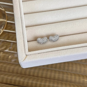 Detailed close-up of heart-shaped earrings with micro-pave cubic zirconia on a velvet box
