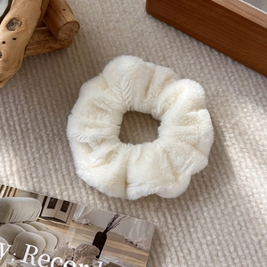 Dettaglio dell'elastico in peluche bianco panna con morbida ecopelliccia su vassoio