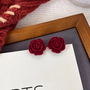 Nahaufnahme von Vintage dunkelroten beflockten Rosenohrringen mit Samttextur für Winter