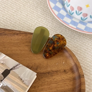 Gros plan de barrettes goutte d'eau en acrylique vert olive et écaille sur bois