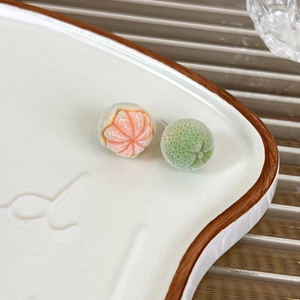 Detailed macro view of flocked orange and green citrus fruit stud earrings