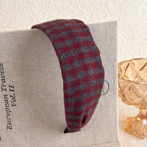 Close-up of vintage red and grey plaid plush headband on a decorative book