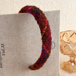 Close-up of a thick bouclé headband in vintage burgundy and brown melange wool fabric