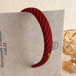Close-up of vintage burgundy twill headband with handmade gold metal tag detailing