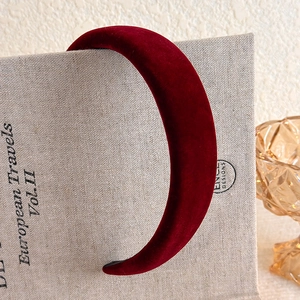 Detail view of the plush burgundy velvet headband texture on a decorative book background
