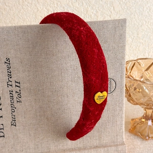 Close-up of vintage burgundy velvet headband with gold heart charm on beige book