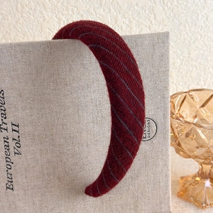 Detail of plush burgundy headband with gray stripes on vintage book background