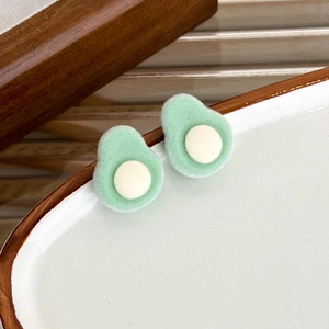 Close-up of cute flocked avocado stud earrings with soft velvet texture on a ceramic dish