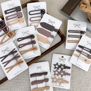 Detail of coffee-toned matte hair clip set featuring geometric stars and waves design