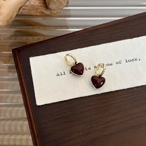 French style red heart earrings with gold hoops on a warm vintage wooden background