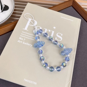 Detailansicht der Aurora Cloud Handy-Perlenkette mit blauen Harzschmetterlingen auf Buch