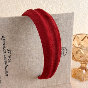 Detail view of vintage burgundy velvet headband on a book showing its matte texture