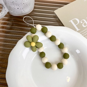 Minimalist olive green flower beaded phone charm strap on a decorative ceramic plate