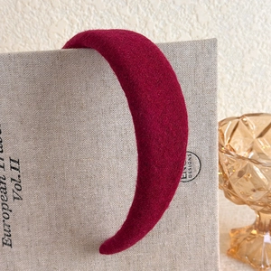 Close-up of vintage burgundy plush headband resting on a textured hardcover book