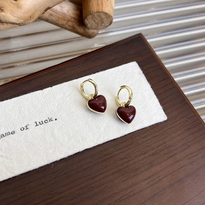 Detail of red heart dangle earrings with gold metal clasp on a vintage wood tray