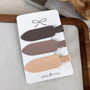 Three earth-toned seamless duckbill hair clips displayed on white card in a wooden tray