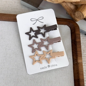 Three-piece set of matte star hair clips in earthy brown tones on a white card display