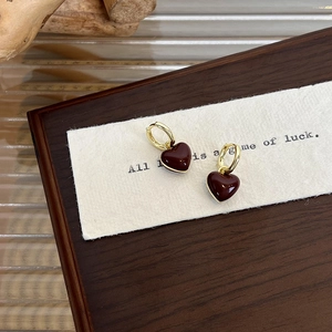Detailed macro shot of vintage red heart earrings with golden hoops on a white card