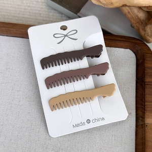 Detailed view of three matte brown wavy hair clips displayed on a white card