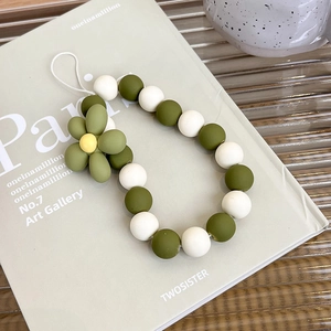 Detail view of mustard green and white beaded phone strap with a cute flower charm