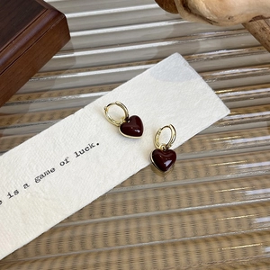 Detail of vintage French heart earrings with red enamel charms and gold hoops on a rustic set