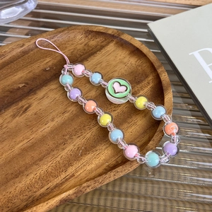 Close-up of handmade candy-colored beaded phone strap with heart charm in a wooden tray