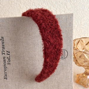 Detailed view of dark red fluffy headband with textured fleece fabric on a book