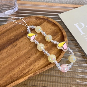 Detail of handmade beaded phone strap with colorful heart charms on a wooden tray