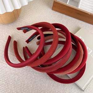 Detail showing a stack of velvet handmade padded headbands in various shades of red