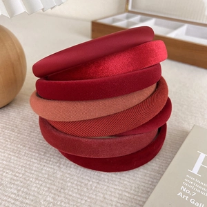 Detail of assorted red headbands in velvet and satin textures for women's hair styling