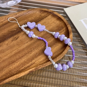 Macro detail of handmade heart beaded phone charm with purple beads and pearls