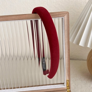 Detail view of a vintage burgundy velvet padded headband on a wooden mirror frame