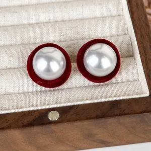 Nahaufnahme von Vintage-Perlenohrringen mit roter Beflockung in einer hölzernen Schmuckbox