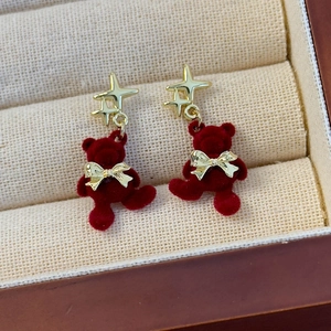 Detailaufnahme roter beflockter Bärenohrringe mit goldenen Sternen und Schleifen