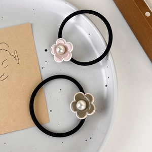 Détail de deux chouchous fleurs avec perles en rose et marron foncé sur une assiette