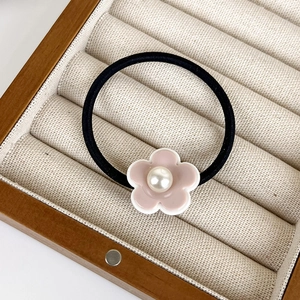 Détail d'un élastique à cheveux fleur crème avec perle dans un coffret à bijoux