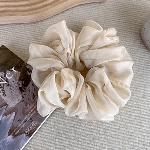 Detail view of cream organza hair scrunchie with soft pleated texture and elegant design