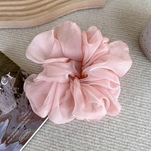 Close-up of pink organza scrunchie with soft pleats on a minimalist aesthetic background