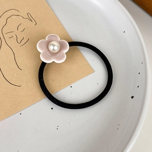 Détail d'un chouchou floral rose crème avec une perle centrale sur un plateau en céramique