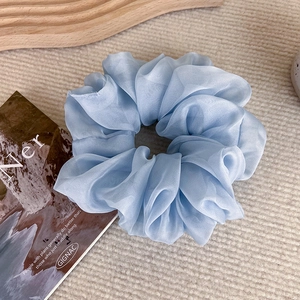Close-up detail of soft light blue organza scrunchie with elegant layered pleats and texture