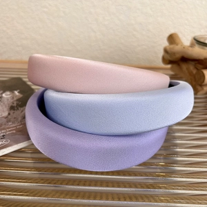 Detailed texture of thick satin sponge headbands in pastel pink, blue, and purple tones