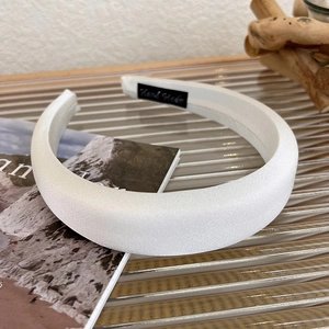 Detailed close-up of white satin padded headband showing high-quality handmade inner label