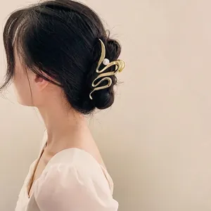 Pince à cheveux dorée ondulée avec perle sur chignon noir, accessoire cheveux minimaliste