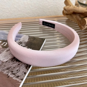 Close-up of light pink satin sponge headband on a textured glass tray and magazine