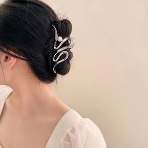 Pince à cheveux argentée ondulée avec perle présentée dans un chignon élégant