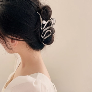 Détail d'une pince à cheveux vague argentée avec perle portée par un mannequin pour le style