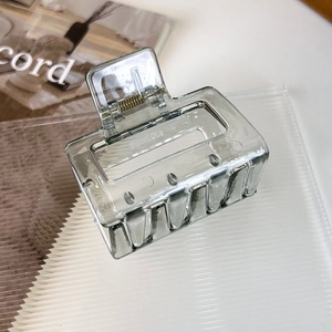 Détail d'une pince à cheveux rectangulaire grise translucide avec ressort en métal doré
