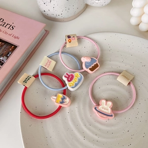 Détail de quatre élastiques à cheveux en résine avec breloques lapin et cupcake sur assiette